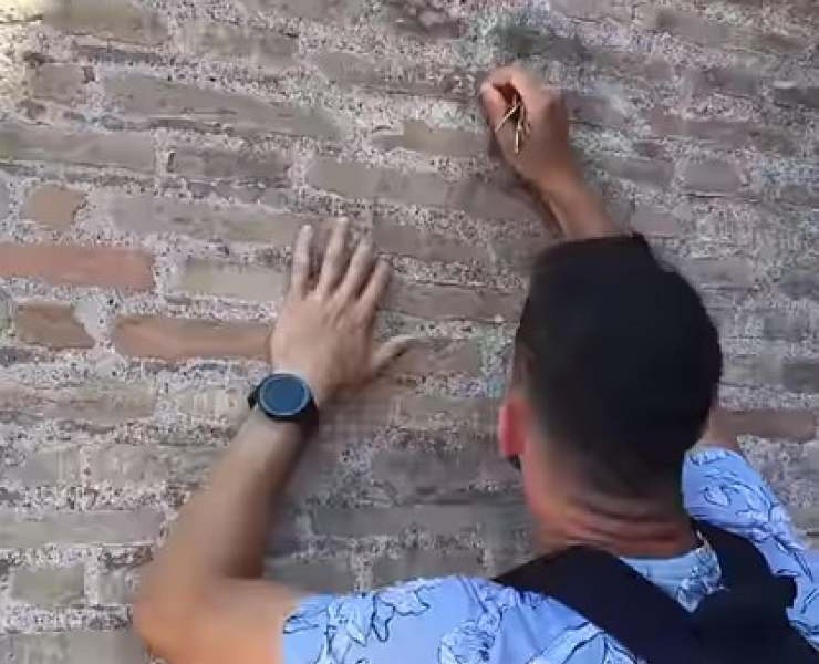 Frame del video pubblicato su Reddit in cui si vede il turista inglese incidere sul Colosseo con delle chiavi il suo nome e quello della fidanzata