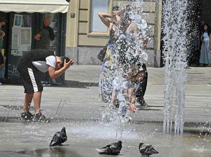 Persone si rinfrescano nelle fontane di piazza Castello a causa del caldo a Torino