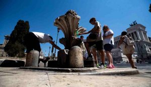 Persone si rinfrescano nella fontana delle Pigne a Piazza Venezia durante l'ondata di caldo