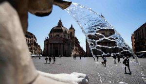 Persone si rinfrescano nella fontana di Piazza del Popolo durante l'ondata di caldo