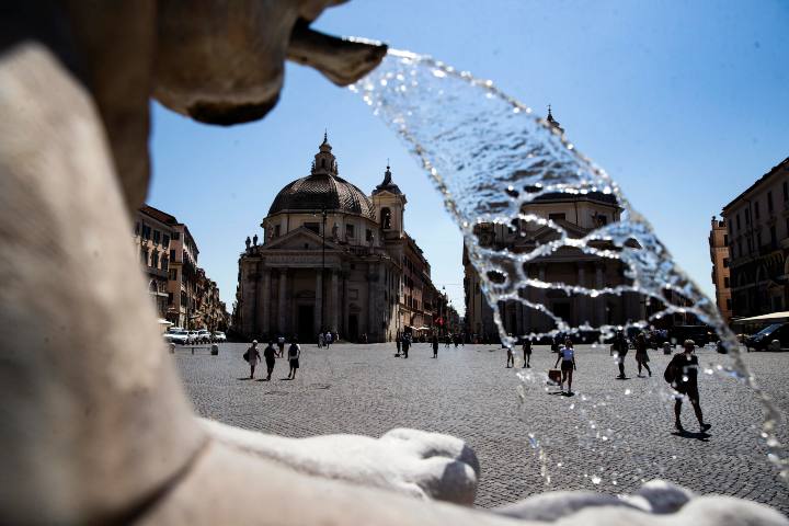 Persone si rinfrescano nella fontana di Piazza del Popolo durante l'ondata di caldo