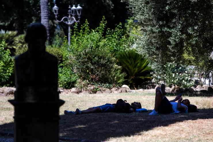 Persone si rinfrescano all'ombra a Villa Borghese, Roma