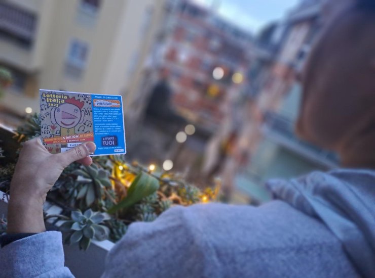 Una donna tiene in mano un biglietto della Lotteria Italia 2023